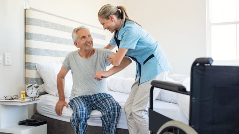 Nurse helping an older man out of bed