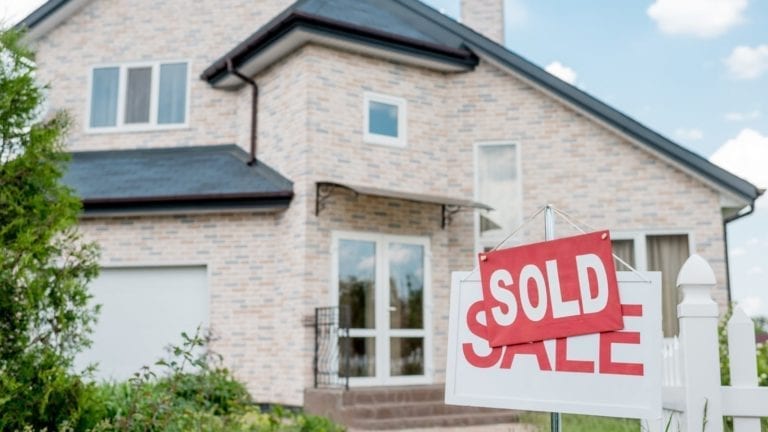 Home with a "sold" sign in the yard