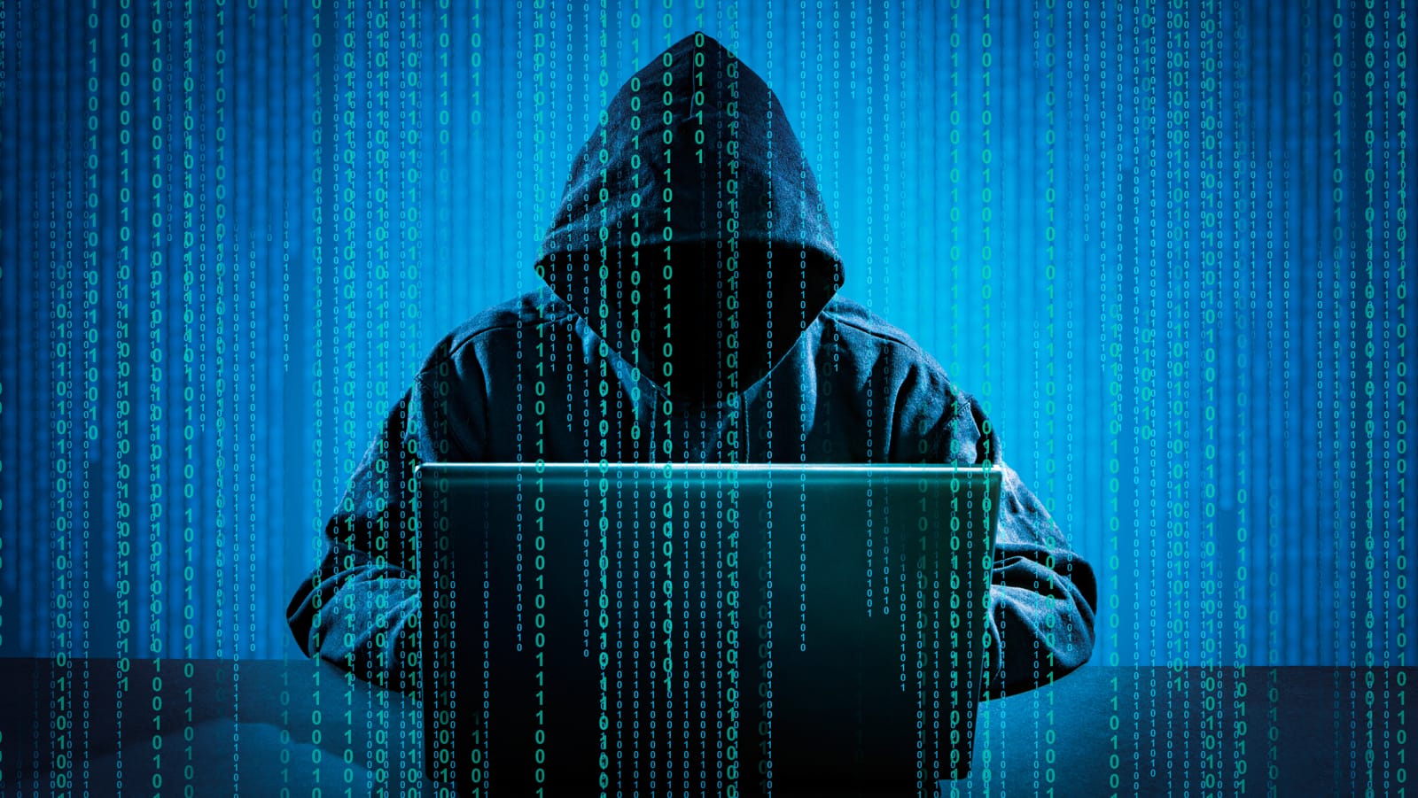 Hacker in a hooded sweatshirt using a laptop