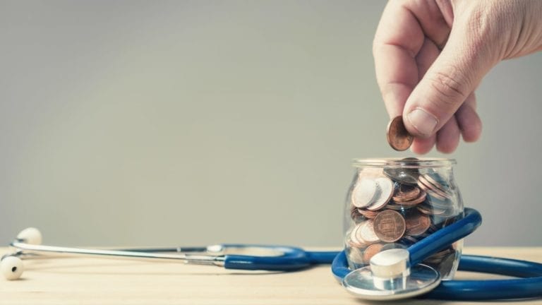 Hand placing coins into a savings jar