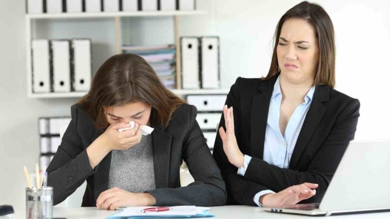 Businesswoman grossed out by her sneezing coworker