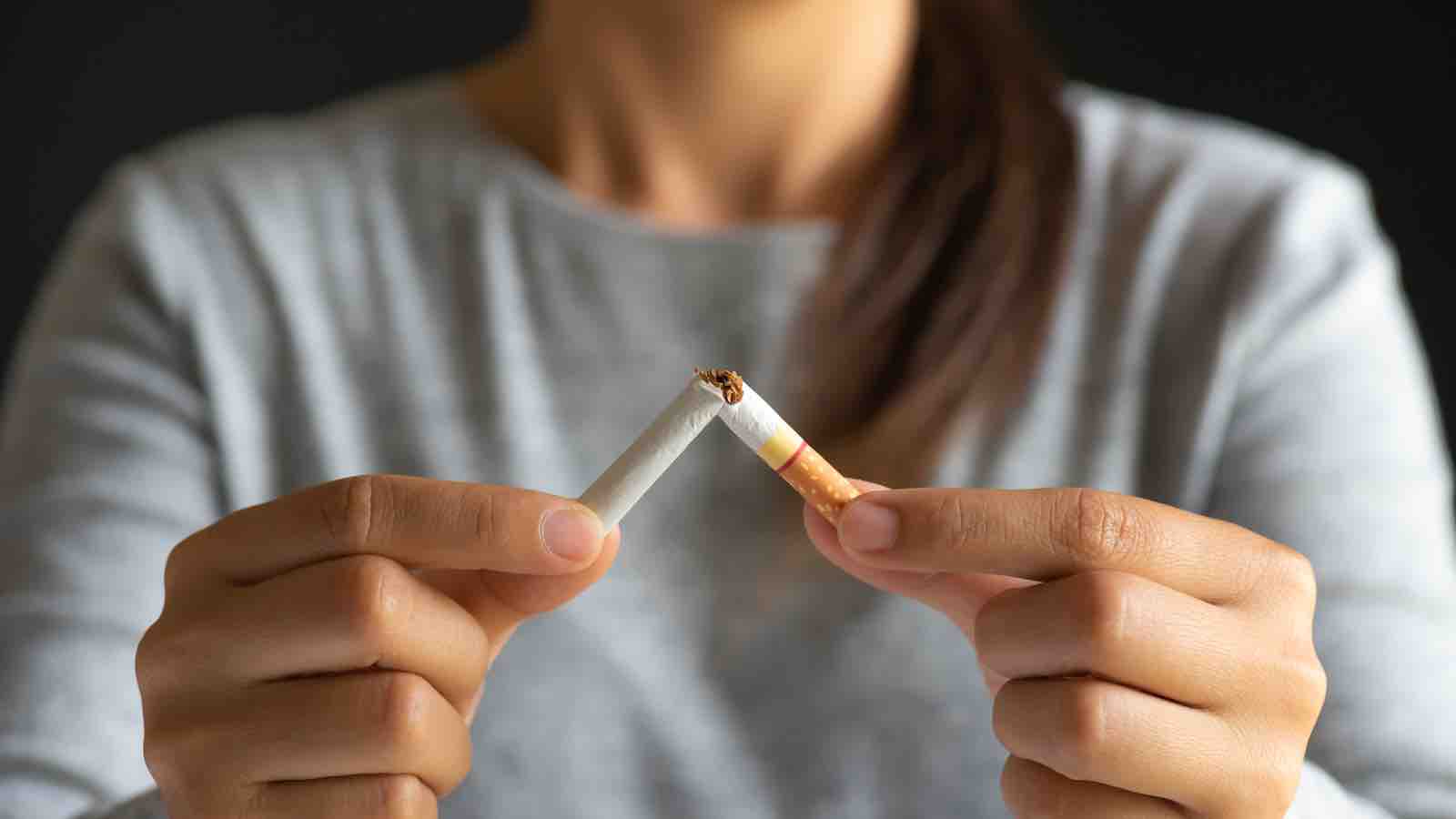 Woman snapping a cigarette in half to quit smoking