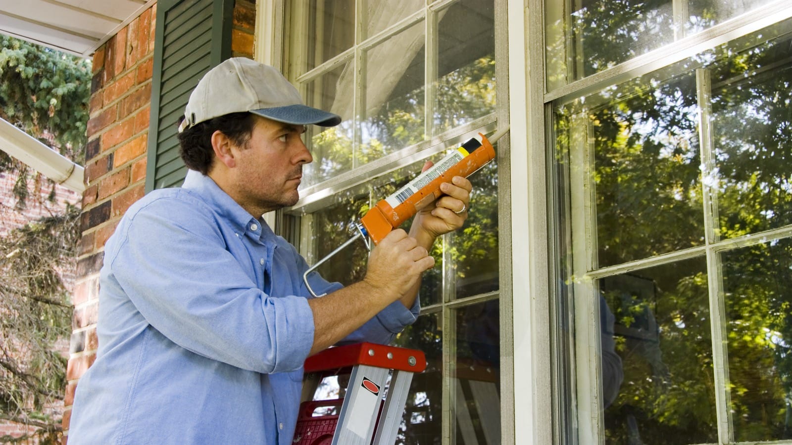 Handyman caulking a window frame