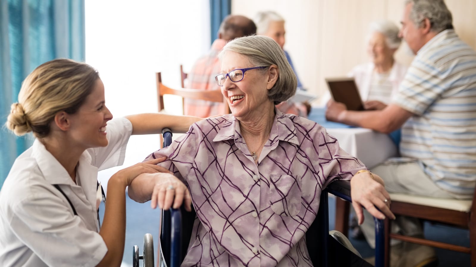 Nurse speaking with a senior woman in a wheelchair in a nursing home