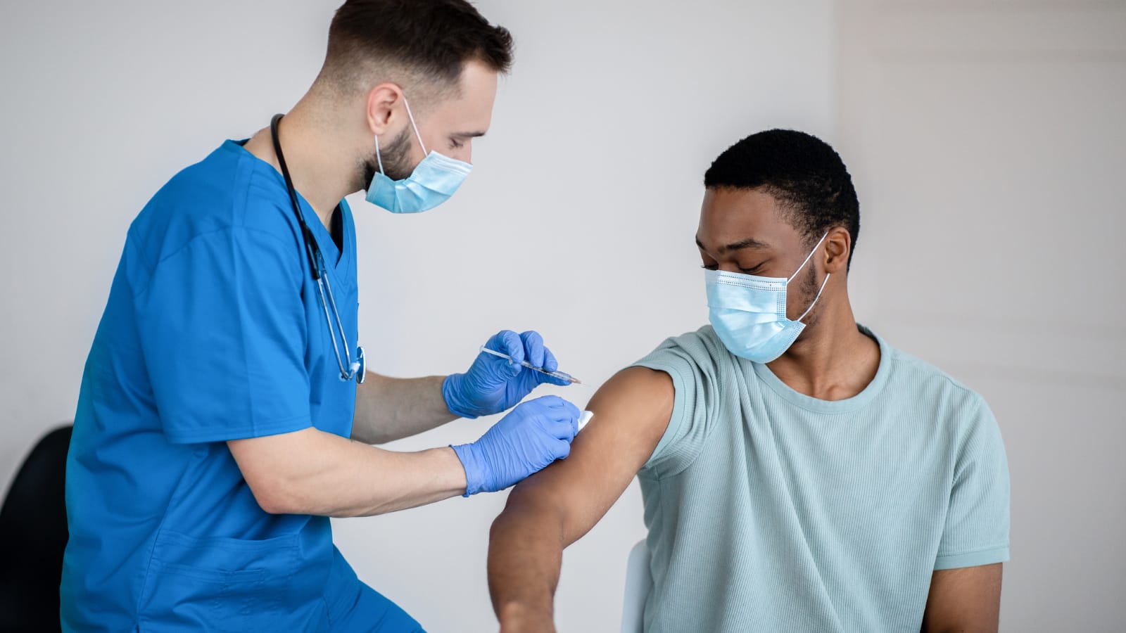 male nurse giving a man the COVID-19 vaccine