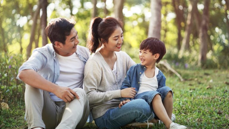 Asian family of three sitting outside