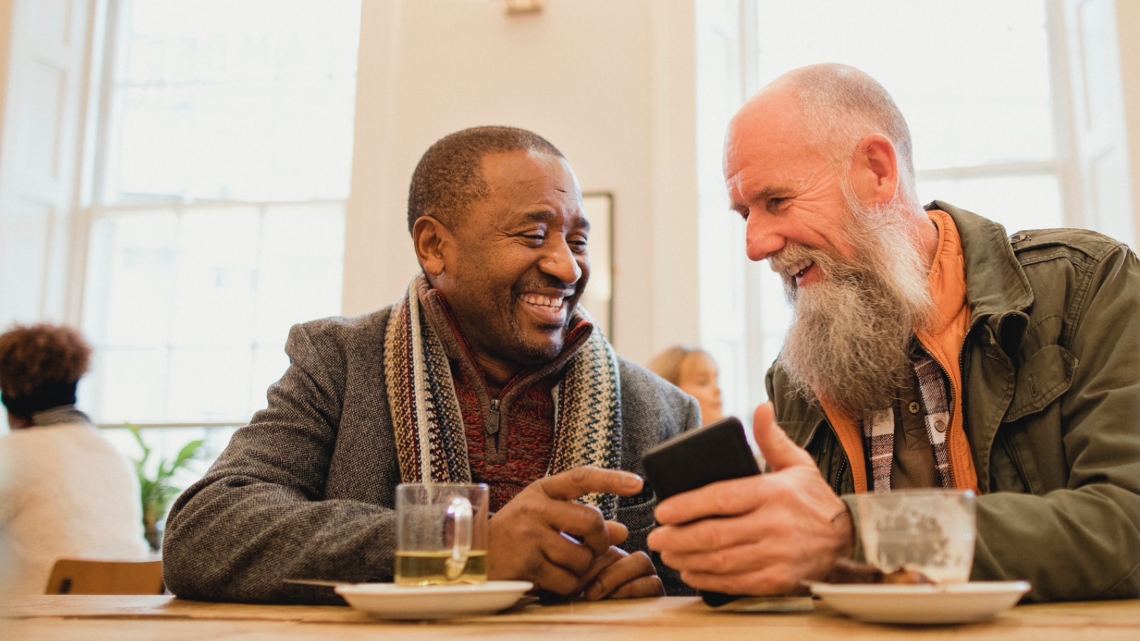 two senior men talking and laughing while sitting in a restaurant