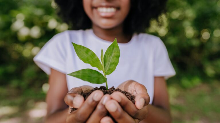 young woman holding a small plant in her hands