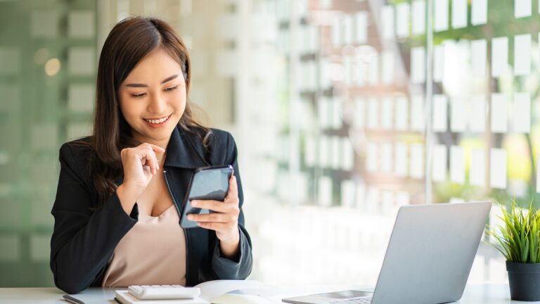 businesswoman smiling while looking at her phone