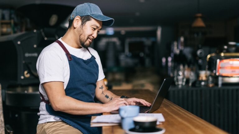 Young male asian business owner reading on his laptop.