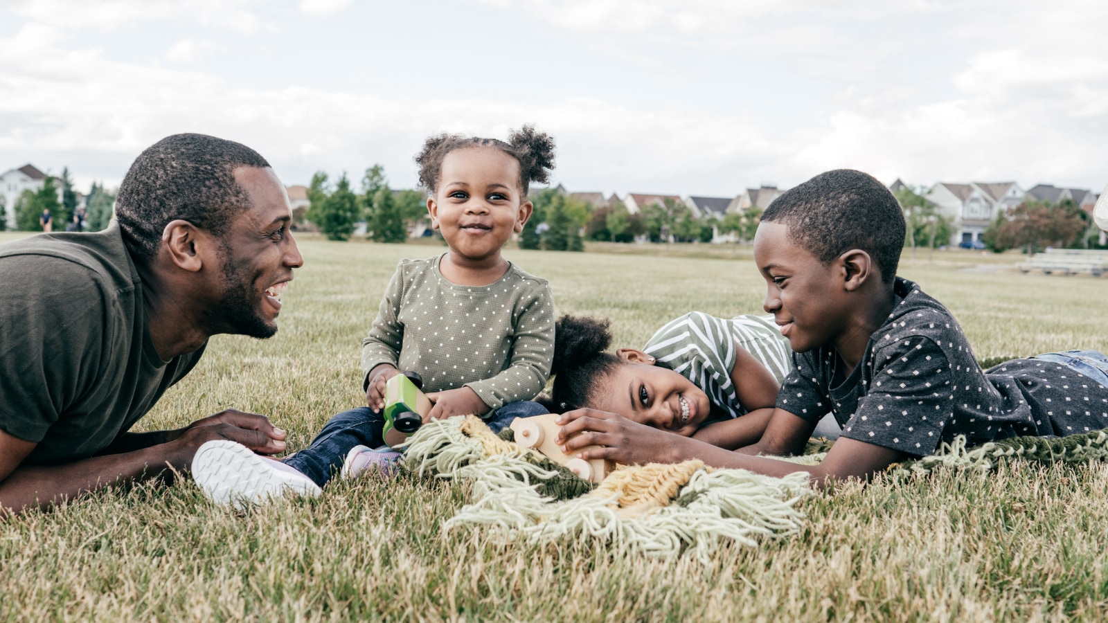 African-American father playing in field with his two young children.