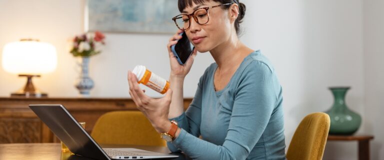 Woman holding prescription bottle while speaking on the phone.