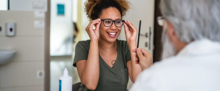 Young woman trying on new glasses at eye doctor.