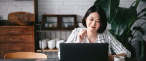 Young woman smiling while working on laptop.