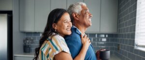 Older couple looking out window and smiling.