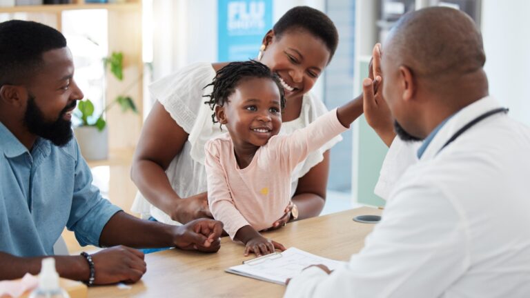 Young family with baby high-fiving doctor.