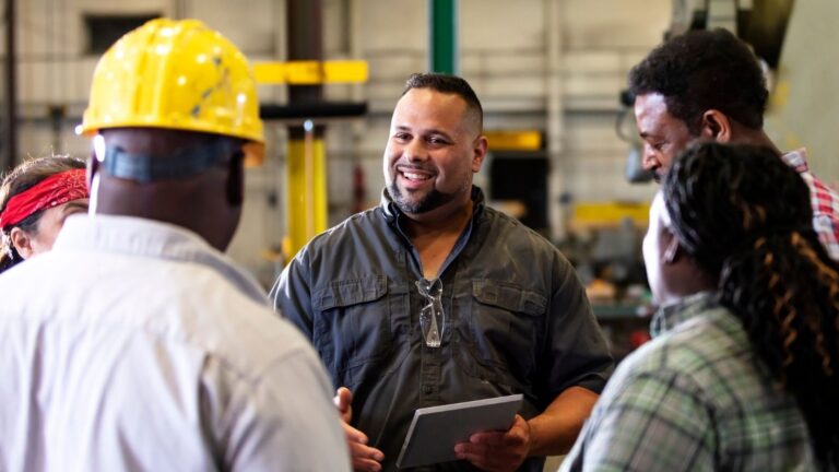 Multiracial group in factory having a conversation.