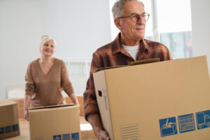 A senior couple carrying cardboard boxes.